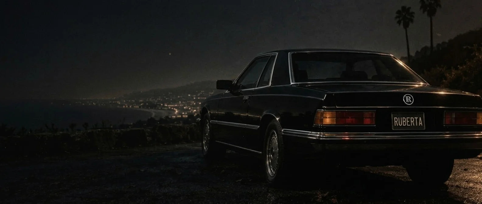 Original night-drive artwork: an unbranded vintage black coupe, autumn leaves and Los Angeles palms after dark